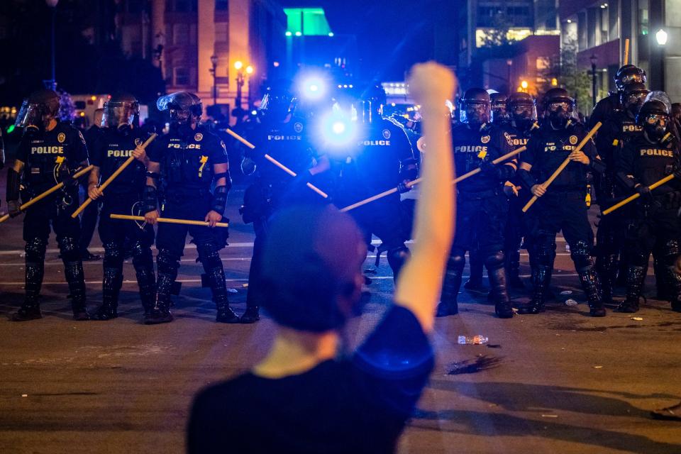 A protester raises a fist into the air early Friday morning as the deaths of Louisville's Breonna Taylor and Minneapolis' George Floyd at the hands of police spurred protests. May 29, 2020