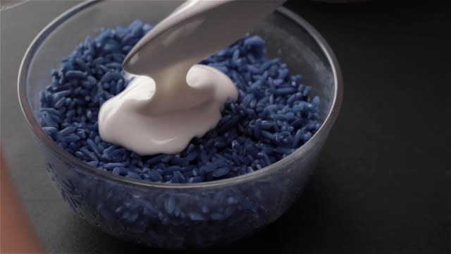 Adding thick coconut milk to blue glutinous rice