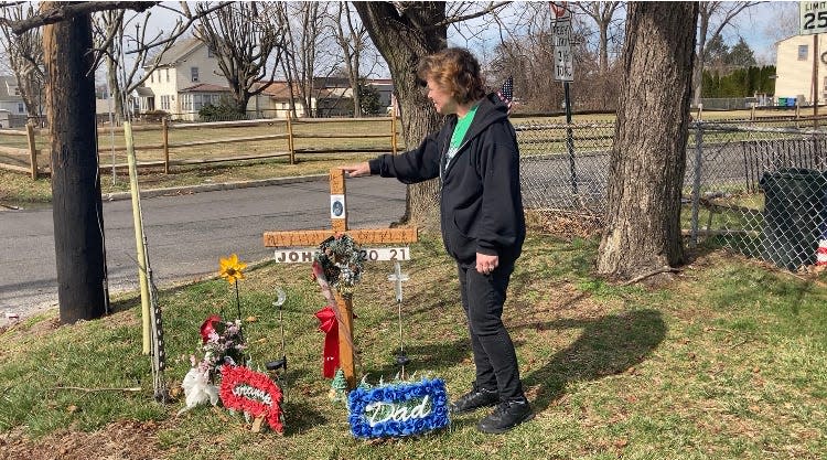 Tina Mazzatenta touches the cross at the roadside memorial for her fiance, John Dugan, a few feet from where he was struck and killed by a hit-and-run driver last Christmas Eve. "Going home just isn't the same without him here," she said.