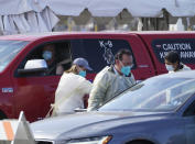 People wait inside their vehicles in line at a mass COVID-19 vaccination site outside The Forum in Inglewood, Calif., Tuesday, Jan. 19, 2021. (AP Photo/Damian Dovarganes)