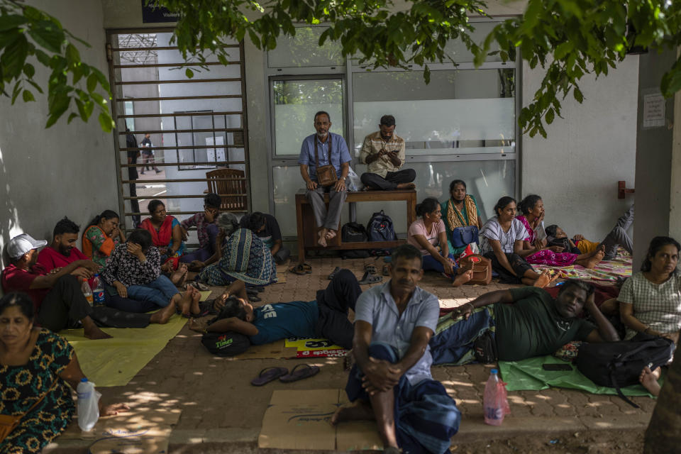 People wait to get their passports outside Department of Immigration & Emigration in Colombo, Sri Lanka, Monday, July 18, 2022. Bankruptcy has forced the island nation's government to a near standstill. Parliament is expected to elect a new leader Wednesday, paving the way for a fresh government, but it is unclear if that's enough to fix a shattered economy and placate a furious nation of 22 million that has grown disillusioned with politicians of all stripes. (AP Photo/Rafiq Maqbool)