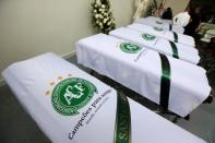 Blankets bearing the crest of Brazilian soccer team Chapecoense are placed on coffins holding the remains of the victims who died in an accident of the plane that crashed into the Colombian jungle with the team's players onboard, in Medellin, Colombia December 1, 2016. REUTERS/Jaime Saldarriaga