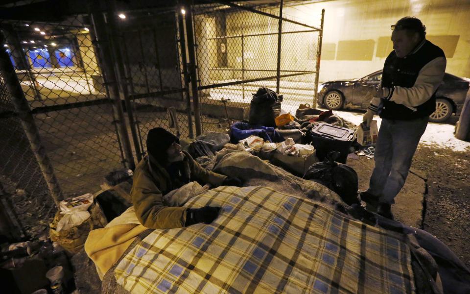 Doctor Patrick Angelo checks on a homeless man under the overpasses on Lower Wacker Drive in Chicago, Illinois, January 7, 2014. Angelo visits the homeless several times a week to hand out food, clothing and blankets to those living on the streets with funding coming from his oral surgery medical practice and profits from his healthcare company. Angelo is in his 13th year doing his charity work. Picture taken January 7, 2014. REUTERS/Jim Young (UNITED STATES - Tags: SOCIETY POVERTY)