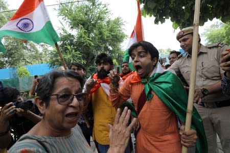 A woman, who was protesting against the scrapping of special constitutional status for Kashmir, argues with people who were celebrating the removal of the special status, during a gathering in New Delhi