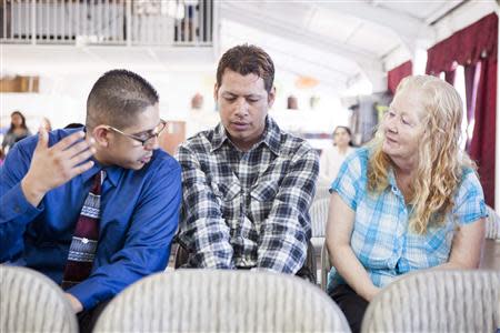 David Amaya and his mother Kathy Amaya talk to each other through translator Juan Soto (L) at Iglesia de Cristo Ministerios Llamada Final in San Diego, California November 24, 2013. REUTERS/Sam Hodgson