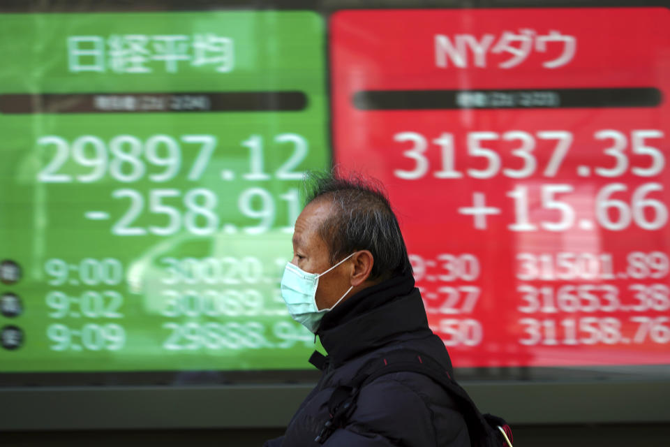 A man wearing a protective mask rides a bicycle in front of an electronic stock board showing Japan's Nikkei 225 and New York Dow indexes at a securities firm Wednesday, Feb. 24, 2021, in Tokyo. Shares fell in Asia on Wednesday as investors weighed the possibility that inflation might prompt central banks to adjust their ultra-low interest rate policies. (AP Photo/Eugene Hoshiko)