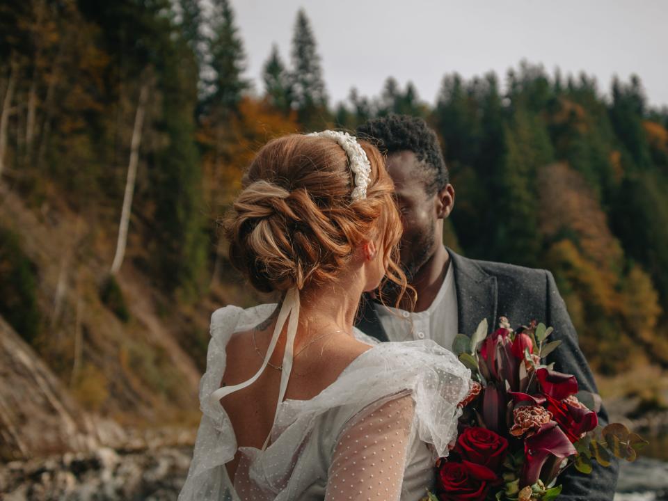 a bride and groom kissing in front of trees