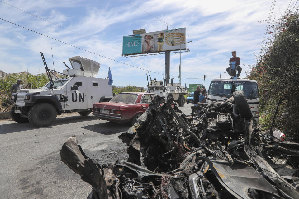 A U.N peacekeeper vehicle passes next to a destroyed car in the southern outskirts of Tyre, Lebanon, Wednesday, March 13, 2024. An Israeli drone strike Wednesday targeting a car in southern Lebanon near the coastal city of Tyre killed a member of Hamas and at least one other person. (AP Photo/Mohammad Zaatari)