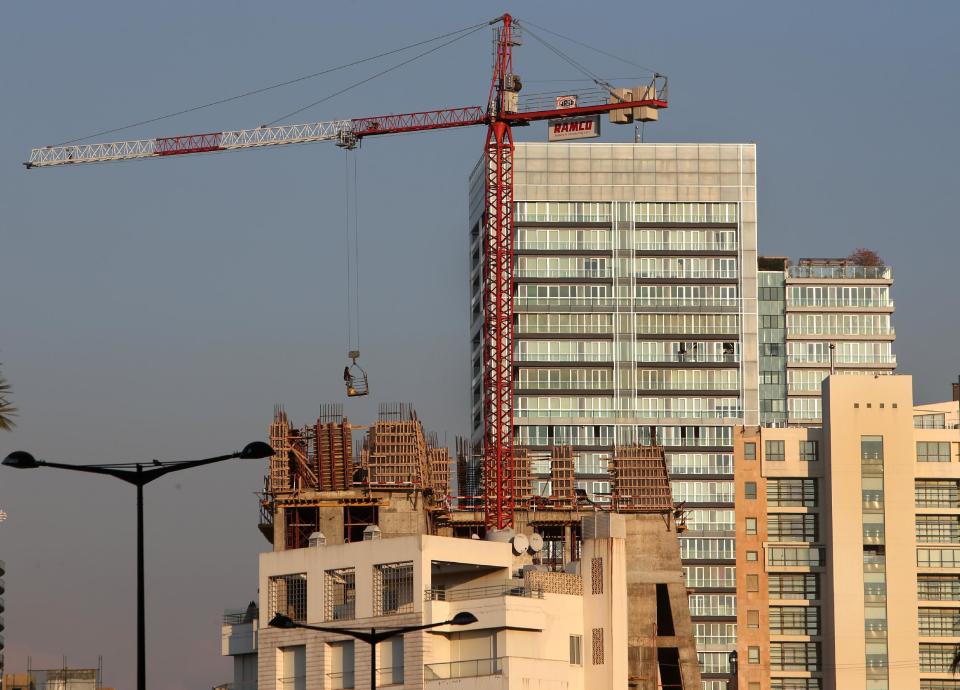 In this February 18, 2014 photo, a construction worker is carried in a basket by a crane, as he works on a luxury tower, in Beirut, Lebanon. Beirut is no different than Dubai, Doha or other major world cities overtaken by a global trend for modern, tall buildings. But in a country that prides itself on its rich history, many complain that Lebanon is losing its charm and character, often said to be the only thing going for it. (AP Photo/Hussein Malla)