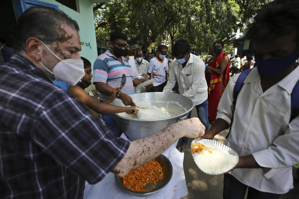 Volunteers wearing face masks as a precaution against the coronavirus serve free food provided by a Hindu temple in Bengaluru, India, Wednesday, June 30, 2021. (AP Photo/Aijaz Rahi)