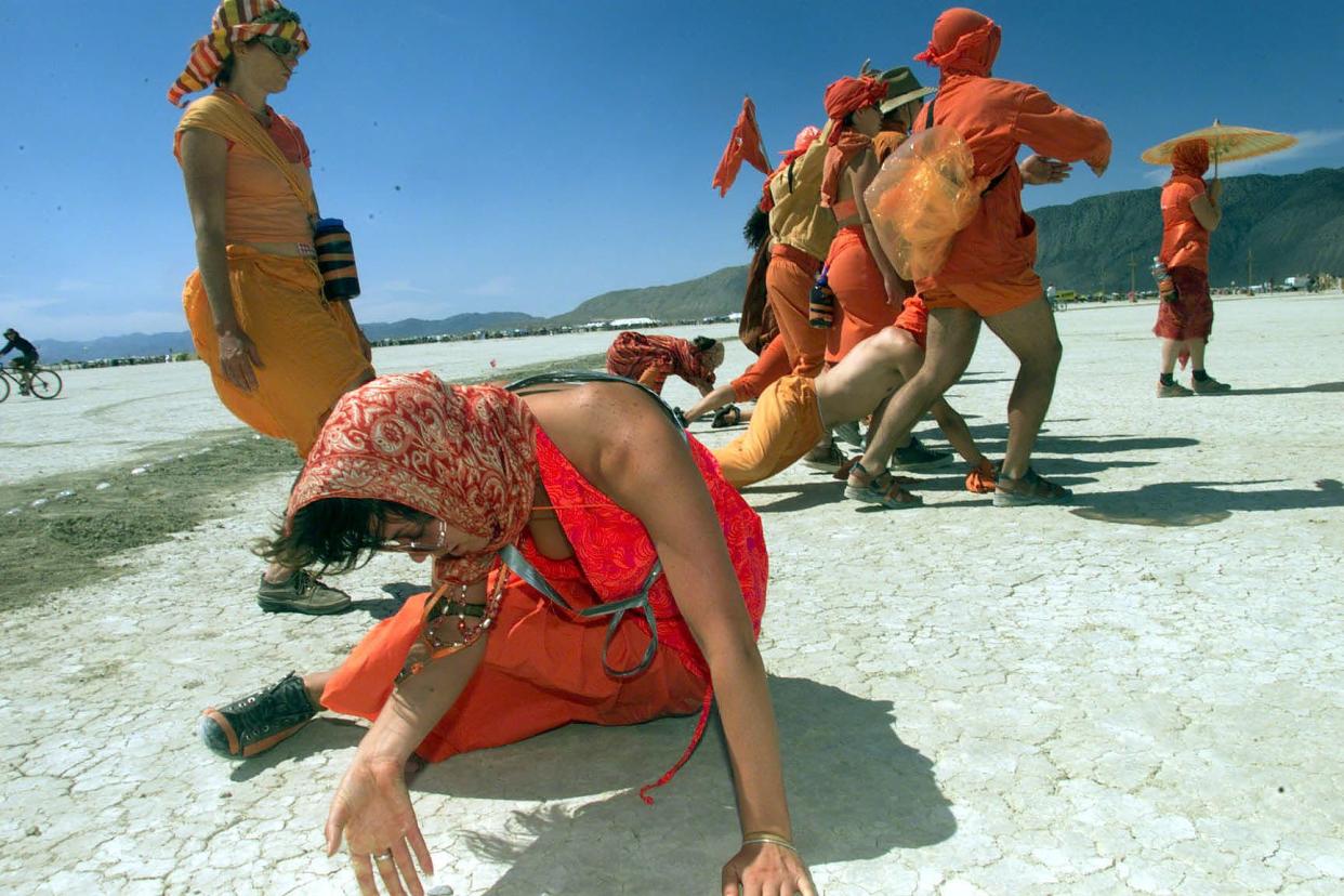 A group of artists, in colorful outfits, perform at the Burning Man festival in September 1999.