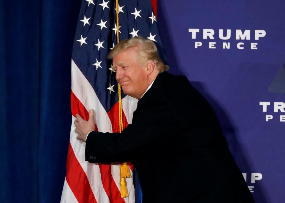 Republican presidential candidate Donald Trump hugs the American flag after speaking at a rally Nov. 7, 2016, in Leesburg, Va.