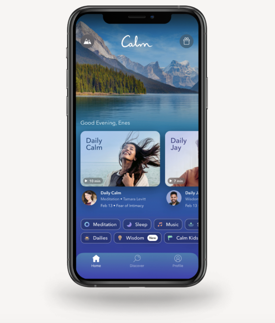 Smartphone displaying the Calm app with meditation and sleep options, set against a mountain background