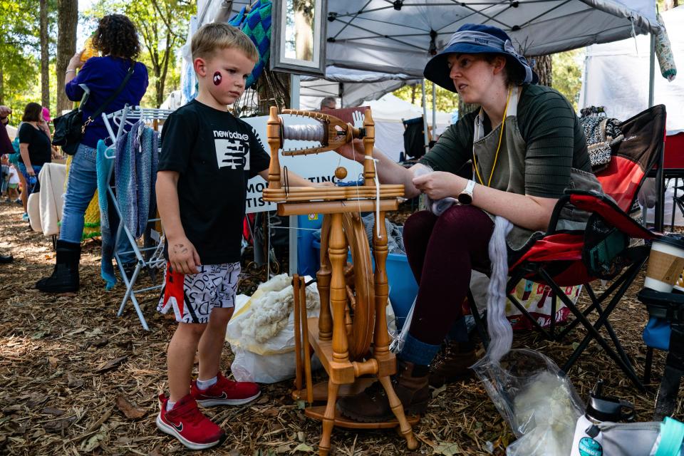 Kristen Snow of the West Alabama Fiber Guild shows B.W. Parish her spinning wheel during the Kentuck Festival of the Arts Saturday, Oct. 15, 2022.
