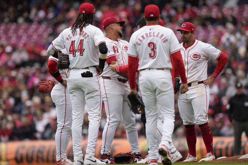 Cincinnati Reds starting pitcher Frankie Montas, center, reacts as his arm is checked after being hit by a line drive by Los Angeles Angels' Taylor Ward in the first inning of a baseball game Sunday, April 21, 2024, in Cincinnati. Montas left the game after the injury. (AP Photo/Carolyn Kaster)