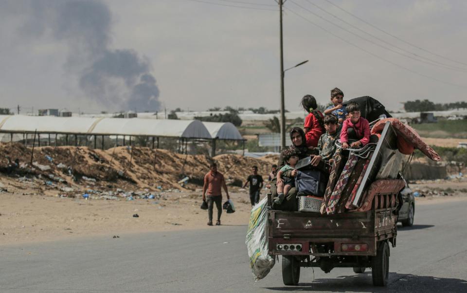 Palestinians fleeing with their belongings ride atop their vehicle in Rafah in the southern Gaza Strip