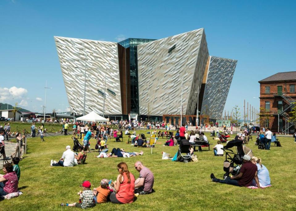 People relax and enjoy the sunshine on the grass area in front of the Titanic Building.