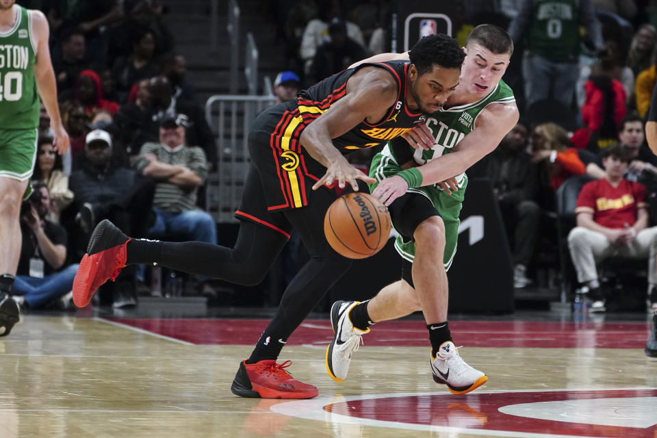 Boston Celtics guard Payton Pritchard (11) reaches in to steal the ball from Atlanta Hawks guard Aaron Holiday (3) during the second half of an NBA basketball game Wednesday, Nov. 16, 2022 in Atlanta. (AP Photo/John Bazemore)