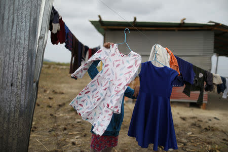 A Venezuelan indigenous girl of Pemon tribe picks her clothes up in the Brazilian indigenous village Tarau Paru in the border city of Pacaraima, Brazil April 12, 2019. Picture taken April 12, 2019. REUTERS/Pilar Olivares