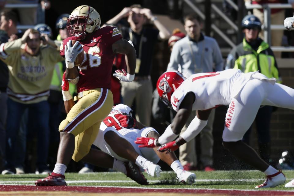 Boston College running back David Bailey (26) scores a touchdown against North Carolina State defensive end Savion Jackson (90) and safety De'Von Graves (14) during the first half of an NCAA college football game in Boston, Saturday, Oct. 19, 2019. (AP Photo/Michael Dwyer)