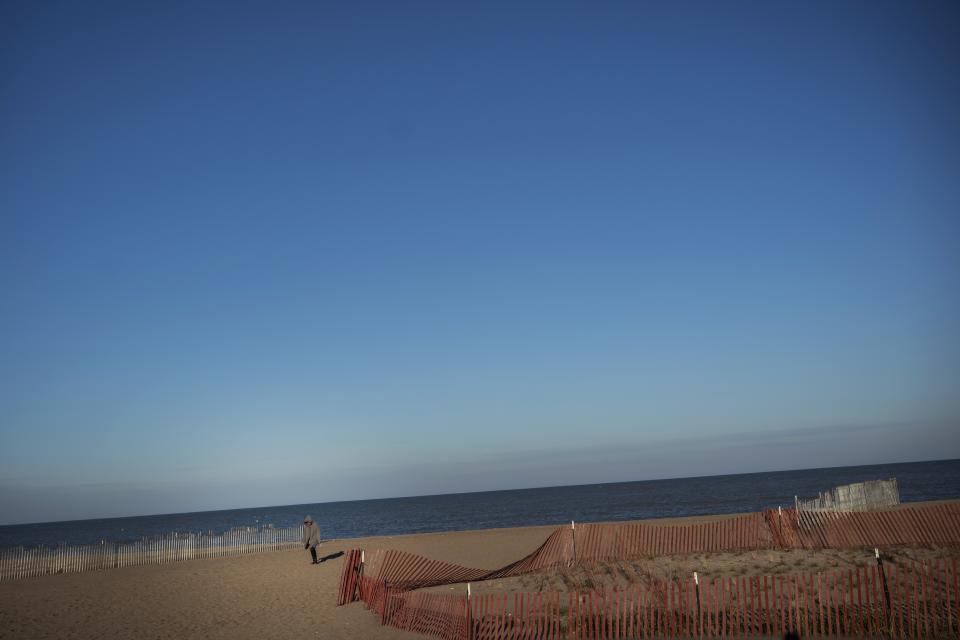 A woman walks on the sand along the Lake Michigan waterfront, Saturday, Oct. 31, 2020, in Kenosha, Wis. (AP Photo/Wong Maye-E)