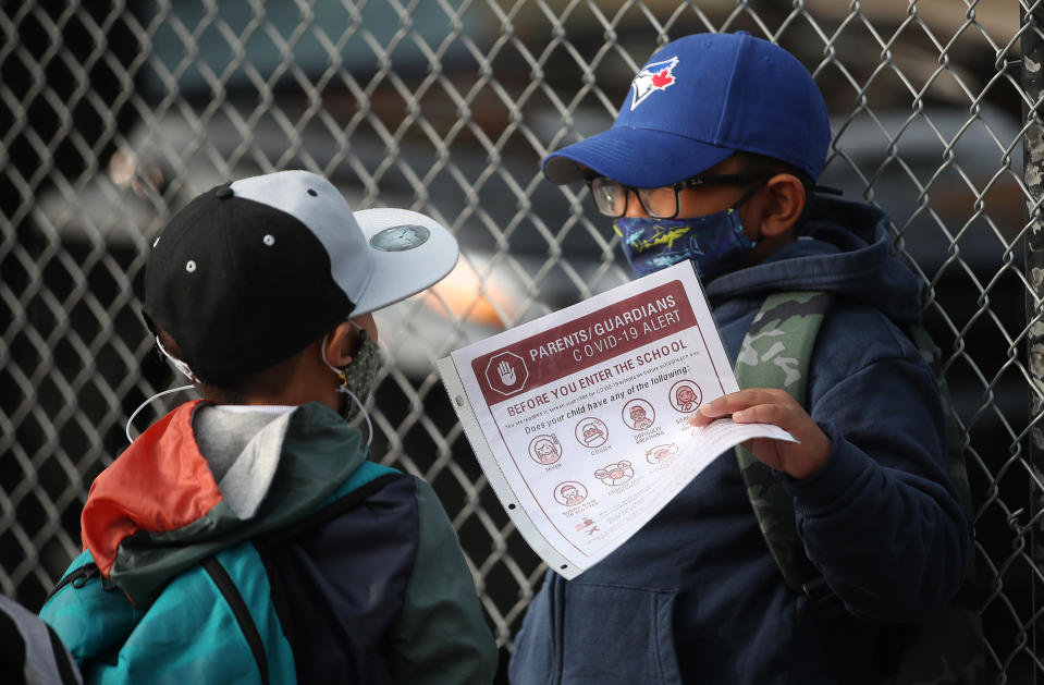 A student in Toronto looks over his COVID-19 Screening Passport while waiting in line to enter his school. (Credit: Steve Russell/Toronto Star via Getty Images)