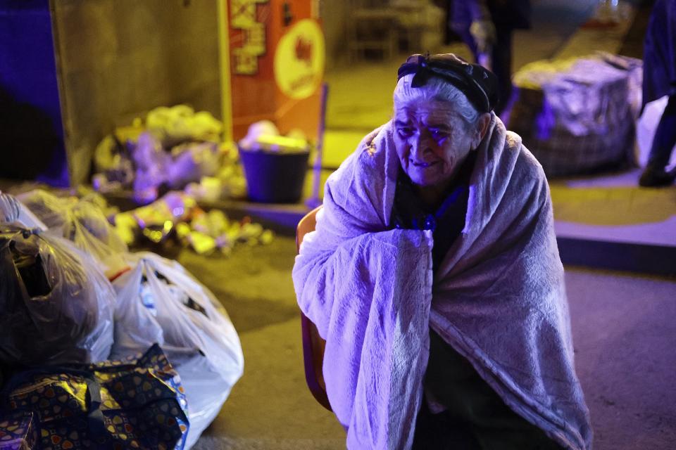 An ethnic Armenian woman from Nagorno-Karabakh warms herself near a tent camp after arriving to Armenia's Goris in Syunik region, Armenia, late Friday, Sept. 29, 2023. Armenian officials say that by Friday evening over 97,700 people had left Nagorno-Karabakh. The region's population was around 120,000 before the exodus began. (AP Photo/Vasily Krestyaninov)