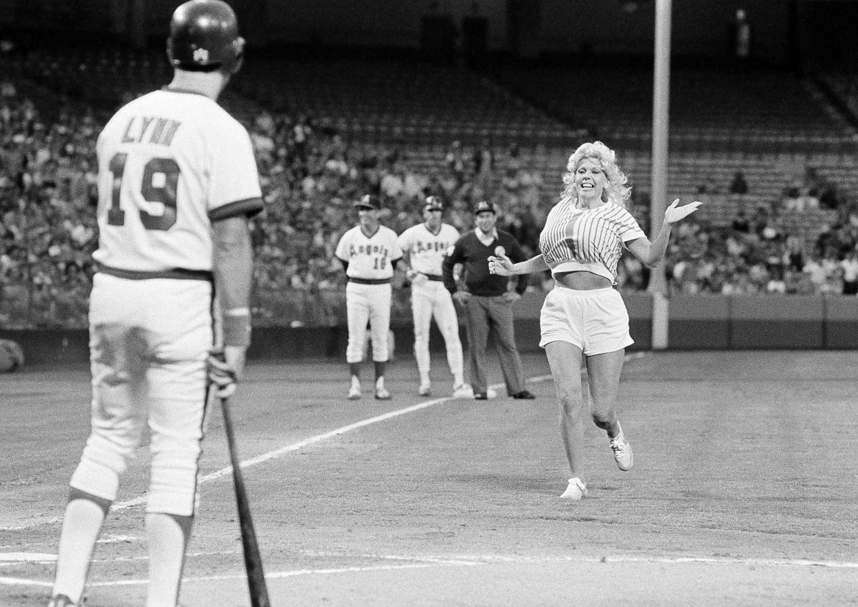 A California Angels fan known as Morganna, runs across the field toward Angels' Fred Lynn to give him a kiss during the first inning in the game with the Chicago White Sox at Anaheim, June 9, 1983. Morganna, on a number of occasions, has run onto the field and kissed different players. She was taken to the Anaheim city police department and booked for trespassing. (AP Photo/Lennox McLendon)