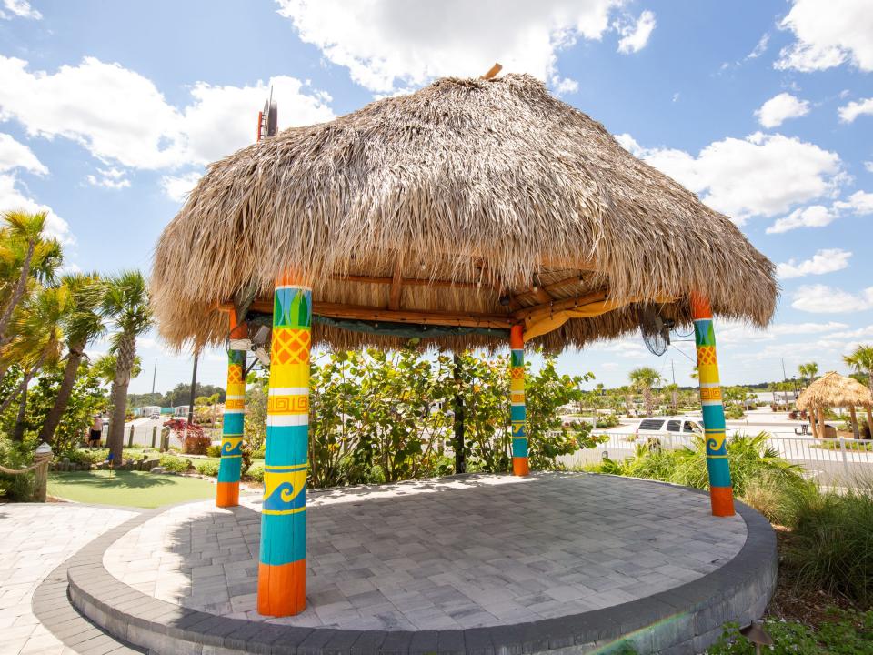 A shaded outdoor area with a thatched roof among trees.