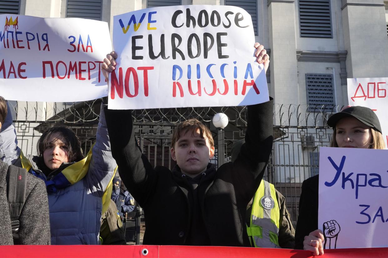 Protesters hold posters in front of the Russian Embassy in Kyiv, Ukraine, Tuesday, Feb. 22, 2022.