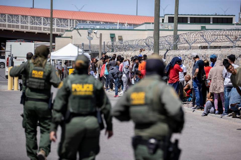 Un grupo de migrantes espera para entregarse a Aduanas y Protección Fronteriza (CBP) en la subestación del puente Paso del Norte, en El Paso, Texas, el martes 9 de mayo de 2023. Los migrantes fueron alentados por agentes de la CBP a entregarse con volantes dejados en la acera en la madrugada mientras dormían afuera de la Iglesia del Sagrado Corazón.