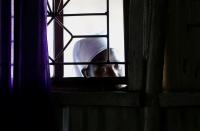 A faithful looks through the window as she follows a mass, amid concerns about the spread of coronavirus disease (COVID-19) at the St. Joanes, Legio Maria African Mission Church within Fort Jesus in Kibera slums of Nairobi