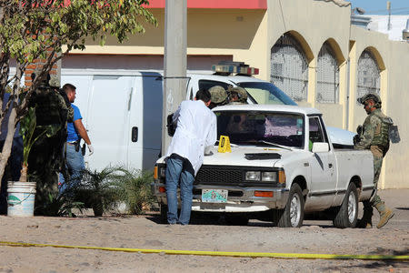 A forensic technician and Mexican marines work at a crime scene after a shooting with unknown assailants in Culiacan, Mexico, February 7, 2017. REUTERS/Jesus Bustamante