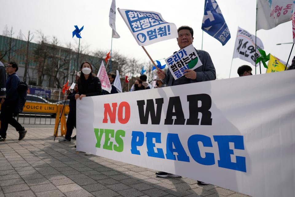 Protesters hold signs during a rally to oppose to the planned the joint military exercises between the U.S. and South Korea, in Seoul, South Korea, Saturday, March 11, 2023.
