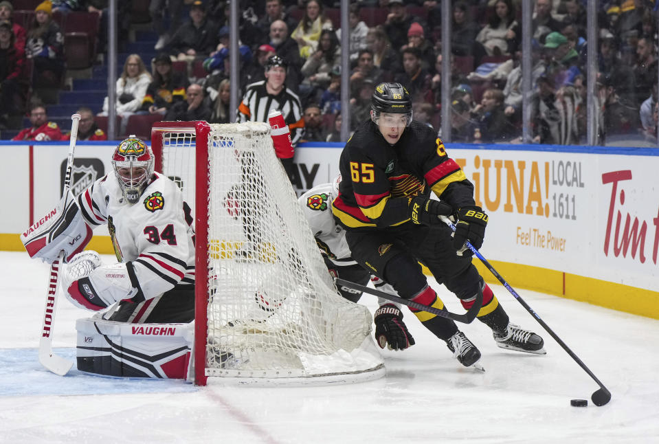 Vancouver Canucks' Ilya Mikheyev (65) skates with the puck behind Chicago Blackhawks goalie Petr Mrazek (34) during the second period of an NHL hockey game in Vancouver, British Columbia, on Monday, Jan. 22, 2024. (Darryl Dyck/The Canadian Press via AP)