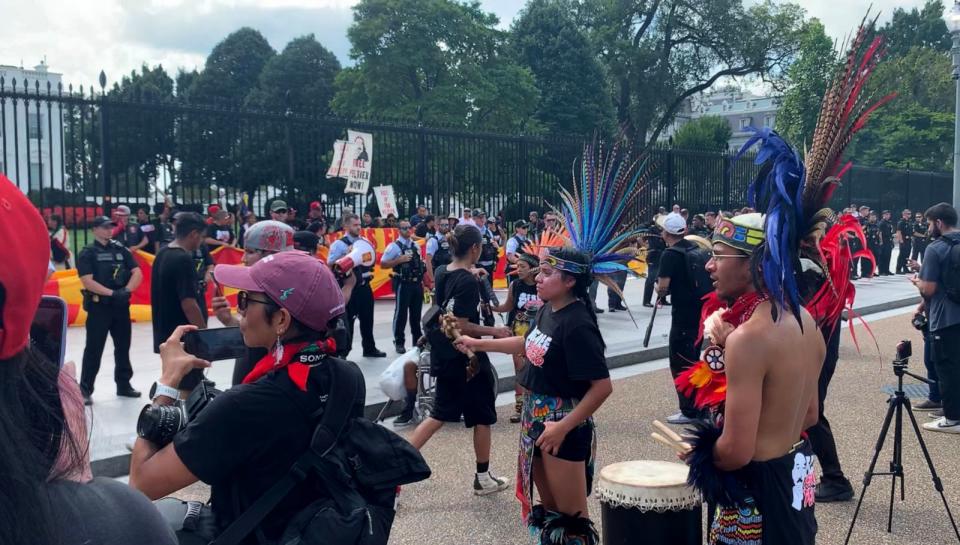 PHOTO: Members of Indigenous communities perform a traditional dance while Secret Service officials line up along the sidewalk. (Mahika Gupta/ABC News)