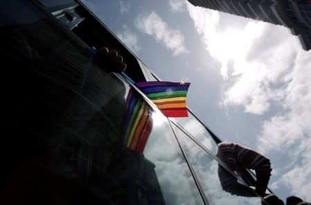 A reveller waves a rainbow flag from a bus during the annual Gay Pride parade along a Central Avenue, in San Jose