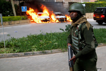 A policeman runs past burning cars at the scene where explosions and gunshots were heard at the Dusit hotel compound, in Nairobi, Kenya January 15, 2019. REUTERS/Baz Ratner