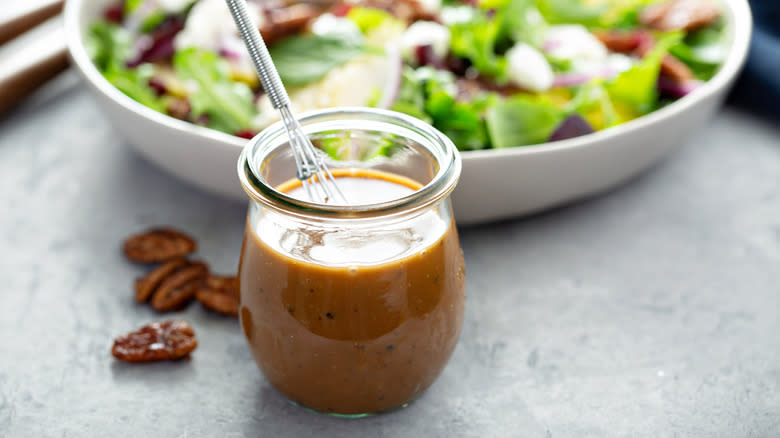 jar of vinaigrette next to a bowl of salad