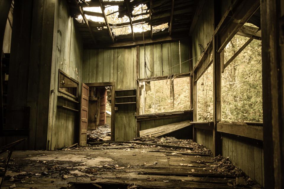 Inside an abandoned cabin with broken windows and a collapsing roof