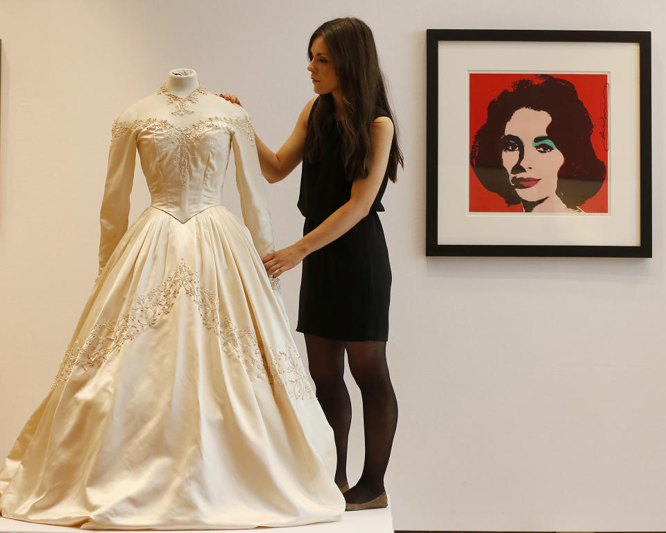 A Christie's employee adjusts Elizabeth Taylor's first wedding dress, designed by the legendary costume designer Helen Rose, at the auction house Christie's in London, Wednesday, June 19, 2013. The wedding dress is part of the auction 120 years of Pop Culture, which is showcasing important memorabilia dating from every decade of the past century of popular culture from the ubiquitous industries of film and music. The estimated price is 30,000 – 50,000 pound (46,000-78,000 dollars). (AP Photo/Frank Augstein)