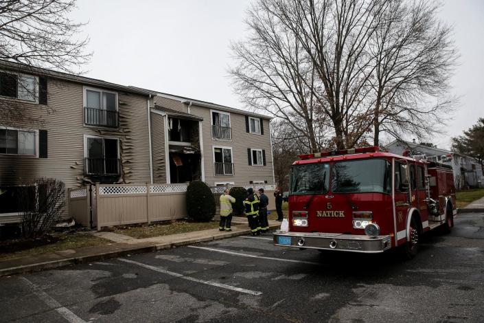 Firefighters stand by after an overnight fire ripped through a multi-unit apartment at 5 Village Way in Natick, Dec. 18, 2021.