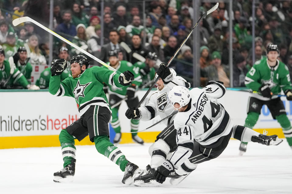 Dallas Stars center Joe Pavelski, left, passes the puck as Los Angeles Kings left wing Kevin Fiala, center, and defenseman Mikey Anderson (44) collide during the first period of an NHL hockey game, Tuesday, Jan. 16, 2024, in Dallas. (AP Photo/Julio Cortez)