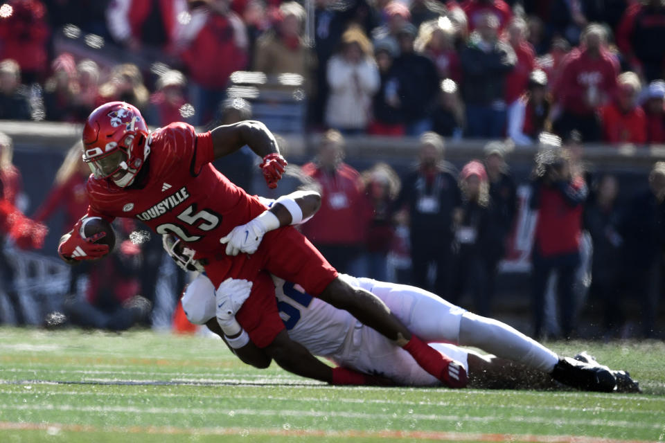 Louisville running back Jawhar Jordan (25) is brought down by Kentucky linebacker Trevin Wallace (32) during the first half of an NCAA college football game in Louisville, Ky., Saturday, Nov. 25, 2023. (AP Photo/Timothy D. Easley)