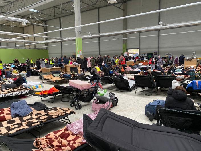 People rest on cots at the crowded refugee center.