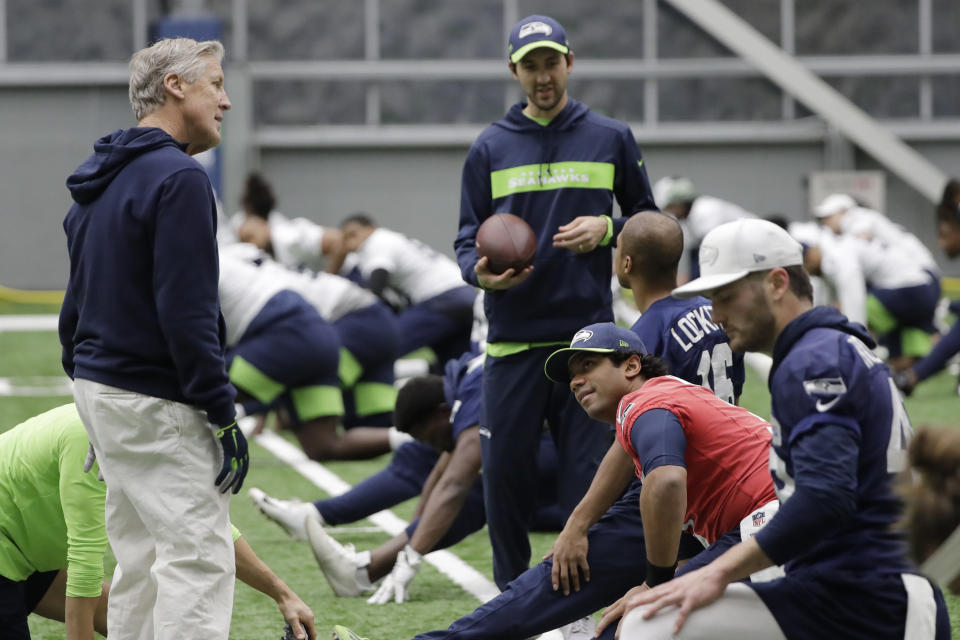 Seattle Seahawks head coach Pete Carroll, left, talks with quarterback Russell Wilson, second from right, during warmups before NFL football practice, Friday, Dec. 27, 2019, in Renton, Wash. (AP Photo/Ted S. Warren)
