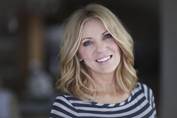 A blonde middle-aged woman in a black-gray striped shirt smiling