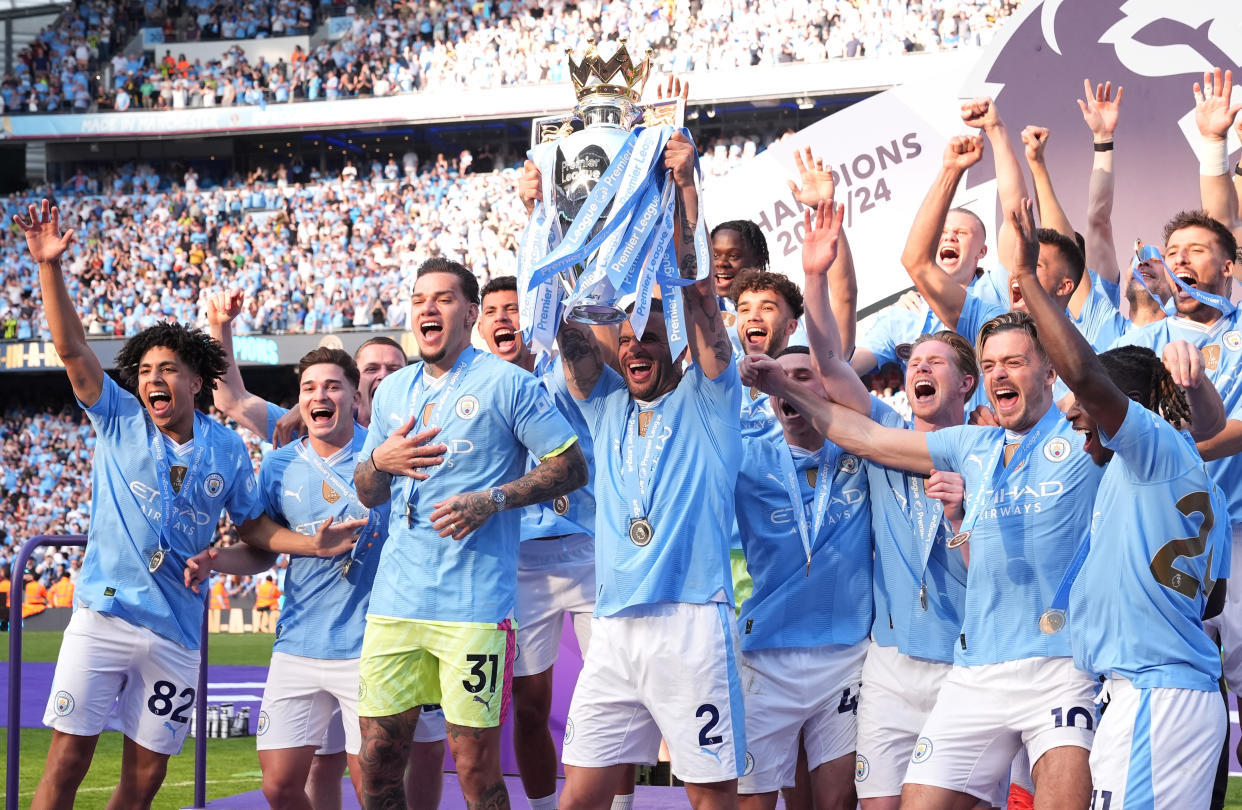 Manchester City's Kyle Walker lifts the English Premier League trophy with team-mates.