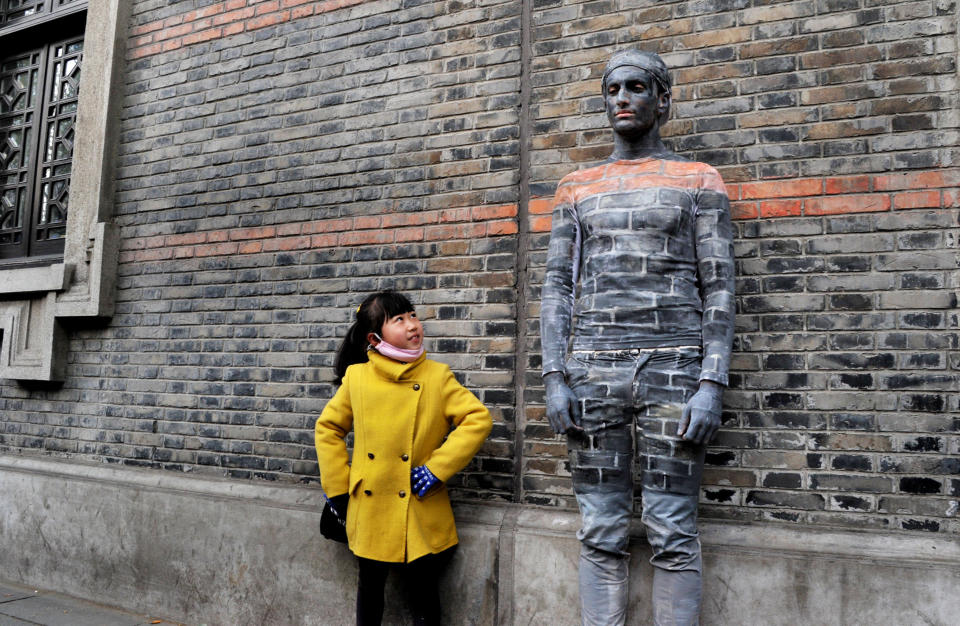 A girl poses with a man disguised as a wall in Shanghai, China, on April 10.