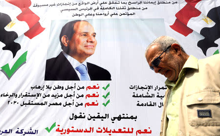 FILE PHOTO: A man walks in front of a banner reading, "Yes to the constitutional amendments, for a better future", with a photo of the Egyptian President Abdel Fattah al-Sisi before the approaching referendum on constitutional amendments in Cairo, Egypt April 16, 2019. REUTERS/Mohamed Abd El Ghany/File Photo